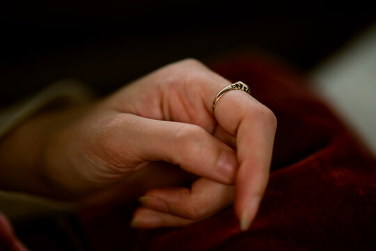 A hand with a gold ring rests gently on a textured red fabric background. Chengdu, Sichuan, China