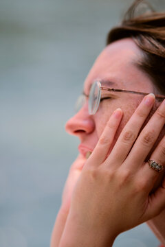 Close-up of a woman with glasses holding their face with both hands and eyes closed. Li River, Li Jiang, Guangxi, China