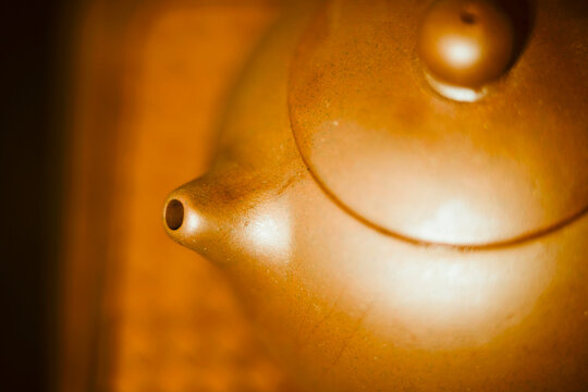 Close-up of a smooth brown teapot spout and lid on a wooden surface. Guangzhou, Guangdong, China