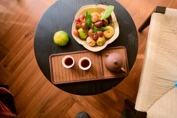 Elegant tea set and fruit arrangement on a black round table with wooden floor backdrop Trip from Guilin to Chengdu, Guangxi, Sichuan, China