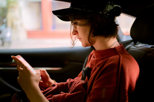 Person wearing a cap using a smartphone in the backseat of a car. Trip from Guilin to Chengdu, Guangxi, Sichuan, China