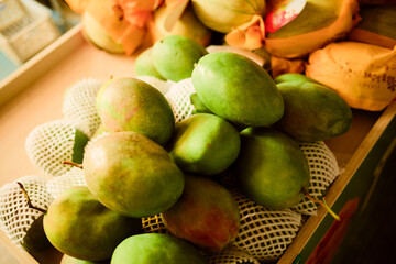 A pile of fresh, green mangoes with protective netting in a grocery setting. Trip from Guilin to Chengdu, Guangxi, Sichuan, China