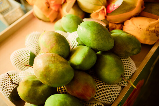 A pile of fresh, green mangoes with protective netting in a grocery setting. Trip from Guilin to Chengdu, Guangxi, Sichuan, China