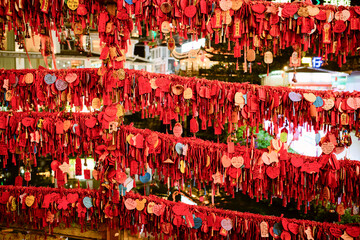 Rows of red paper tags with wishes hang from ropes at a vibrant outdoor festival setting. Trip from Guilin to Chengdu, Guangxi, Sichuan, China
