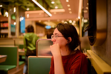 A person with glasses and short dark hair sits in a cozy restaurant with warm lighting. Hongkong, China