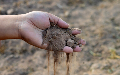 Farmer's hand pouring dry soil, agriculture and environment conservation concept