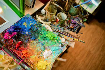 Colorful painter's palette with brushes and mixed vibrant paints in an art studio. Shanghai, China