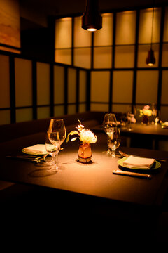 Dimly lit restaurant table set for two with elegant decor and warm ambient lighting. Shanghai, China