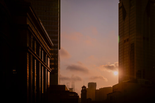 City skyline with tall buildings at sunset, with a warm golden hue and soft clouds. Shanghai, China