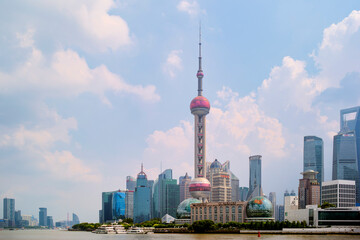 Shanghai city skyline with iconic Oriental Pearl Tower on a bright, partly cloudy day. Shanghai, China