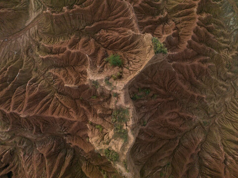 Aerial view of rugged, eroded landscape with sparse greenery and deep reddish-brown tones. Tatacoa Desert, Desierto de La Tatacoa, Colombia