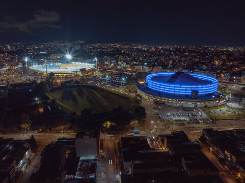 Aerial view of vibrant cityscape at night with illuminated stadiums and bustling streets. Bogota DC, Colombia