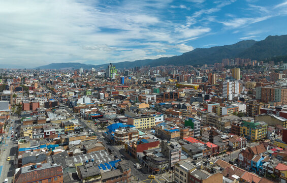 Aerial view of a sprawling cityscape beneath a bright blue sky with scattered clouds. Bogota DC, Colombia