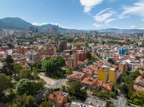 Aerial view of a vibrant cityscape surrounded by mountains under a clear blue sky. Bogota DC, Colombia