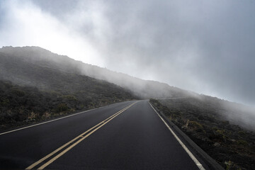 Misty mountain road with fog and low clouds creating a mysterious and serene atmosphere. Kula, Hawaii, USA