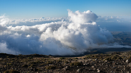 Expansive view of fluffy clouds over rugged mountain terrain under a clear blue sky. Kula, Hawaii, USA