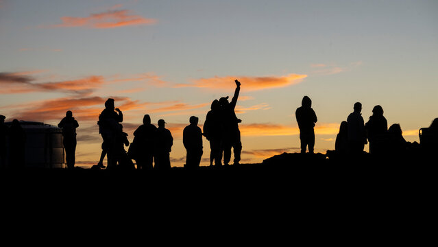 Silhouettes of people against a colorful sunset sky with vivid orange clouds. Kula, Hawaii, USA