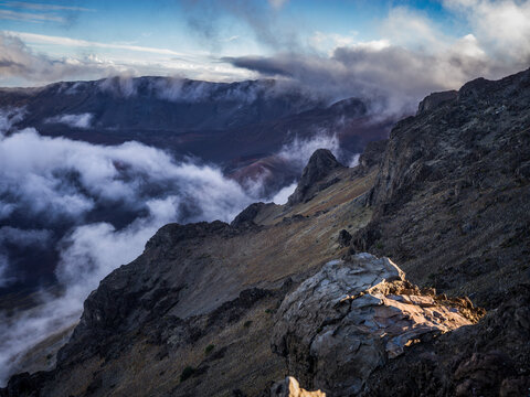 Rugged mountain landscape with dramatic clouds and misty valleys at sunrise. Kula, Hawaii, USA