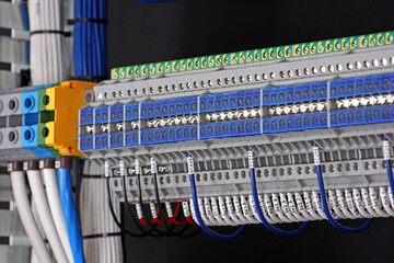 Electrical terminals with connected insulated wires with metal lugs. It is installed on a metal mounting rod in the electrical panel. 
