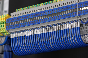Electrical terminals with connected insulated wires with metal lugs. It is installed on a metal mounting rod in the electrical panel. 