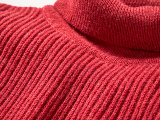 Close-up of red ribbed turtleneck sweater showing texture and stitching.
