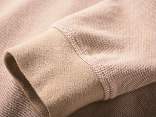 Beige textured fabric sleeve with ribbed cuff in close-up detail.