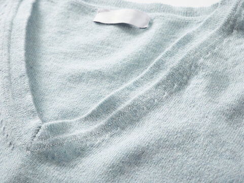 Light gray V-neck sweater close-up with visible texture and fabric details