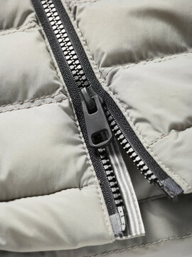 Close-up of a gray jacket zipper detail with quilted fabric texture.