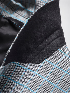 Close-up of a tailored fabric with blue check pattern and black felt detail.