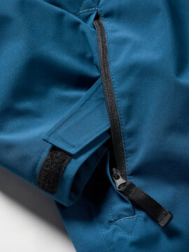 Close-up of a blue jacket with a black zipper and velcro strap detail.