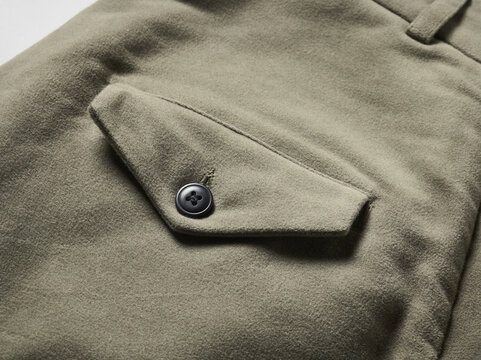 Close-up of an olive green fabric garment with a buttoned pocket.