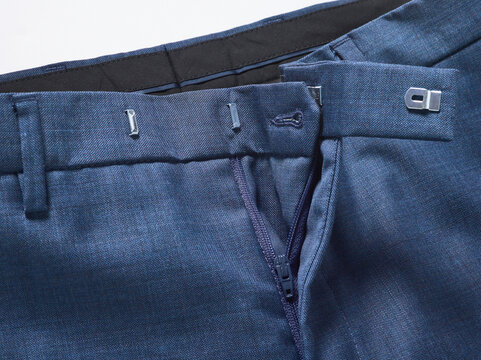 Close-up of blue trousers with visible zipper and belt loops on a white background.