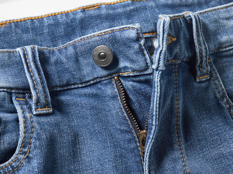 Close-up of blue denim jeans with zipper partially open and button undone.