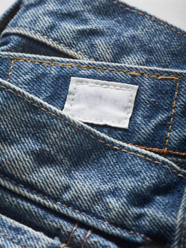 Close-up of folded blue denim jeans with a blank white label stitched on.