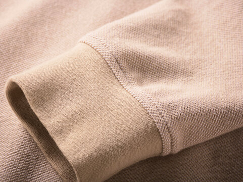 Beige textured fabric sleeve with ribbed cuff in close-up detail.