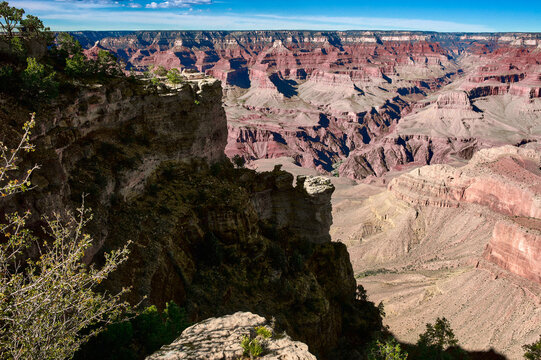 Majestic canyon landscape with layered red and brown rock formations under a blue sky. USA