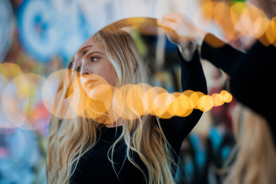 Woman holding a mirror with light reflections against a colorful background WA, USA