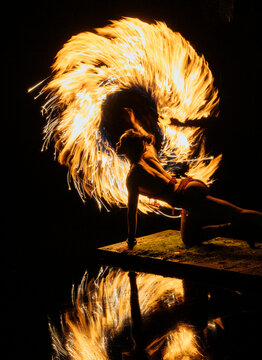 Performer spins fire poi, creating vibrant light trails against a dark background. WA, USA