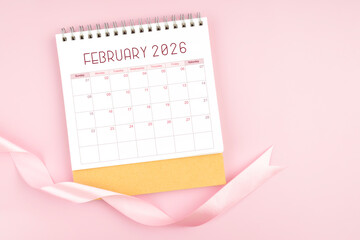 February 2026 desk calendar with pink pastel ribbon.