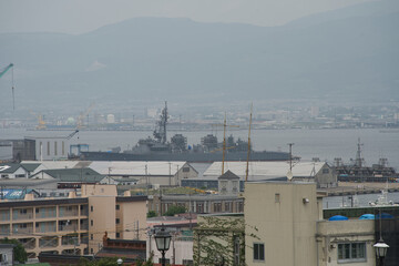 Japanese Naval Vessel Docked at Hakodate Port with Urban Backdrop
