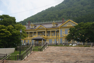 Former Hakodate Ward Public Hall with Stone Steps and Forested Backdrop
