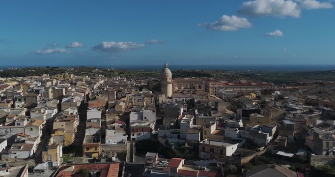 Aerial view of the majestic Noto Cathedral amidst the clustered buildings under a clear blue sky, a scenic blend of architecture, Noto, Sicily, Italy.