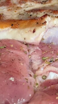 Two pieces of pork sizzling on a black frying pan being flipped with a wooden spatula close up cooking scene showing juicy meat hot steam and delicious culinary action