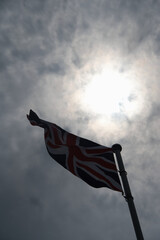 Union Jack Backlit Against a Cloudy Sky
