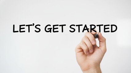 Hand holding a pen writing the motivational phrase let’s get started to inspire goal achievement