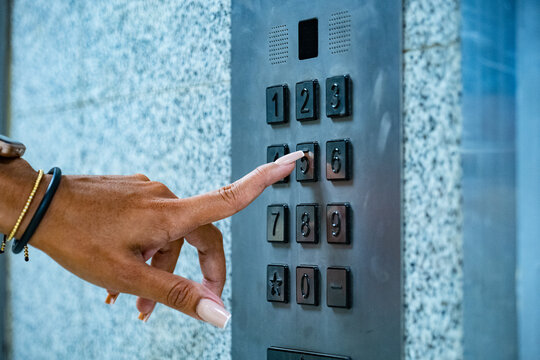 Woman's hands selecting elevator numeric panel