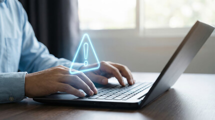 Person working on a laptop with a cybersecurity alert warning symbol indicating potential security risk online