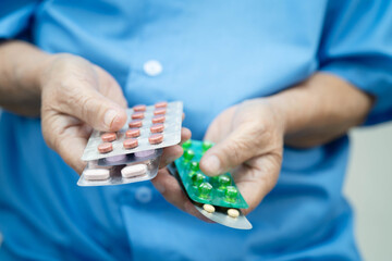 Asian elderly woman holding pill drug in hand, strong healthy medical concept.
