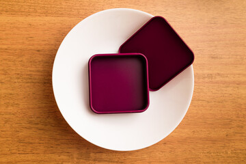 Burgundy metal box mock-up on white plate, top view.