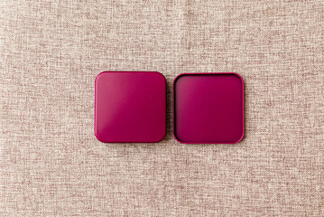 Burgundy metal box mock-up on textile pattern background. Top view.